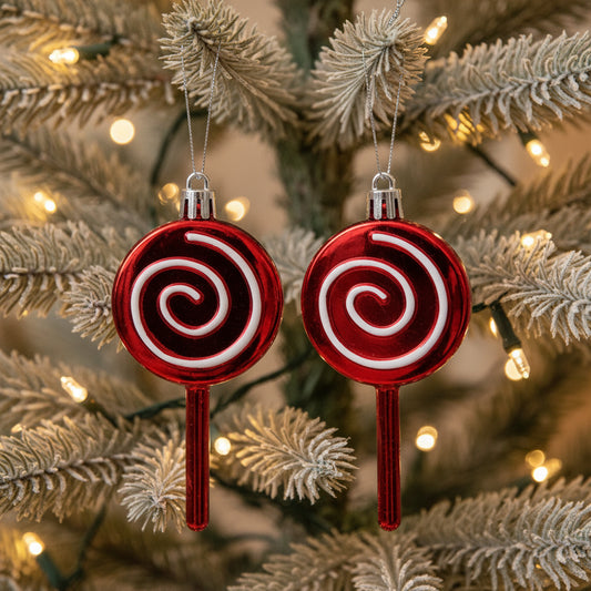 Two red lollipop-shaped Christmas ornaments with white swirls on a white background